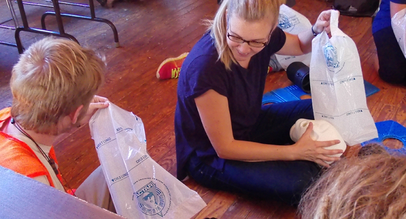Two people hold some sort of plastic bags as they participate in a WFA certification course. 